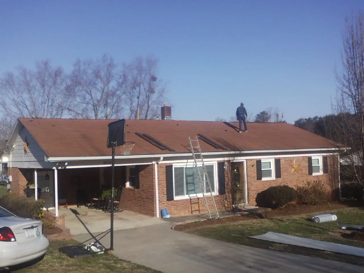 Roofer stripping a shingle roof on a brick ranch before metal panels in Osceola