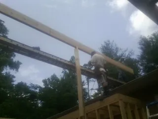 Carpenter setting a ridge beam over a new addition frame — Ice Dam Removal by Roofing Brothers in Osceola